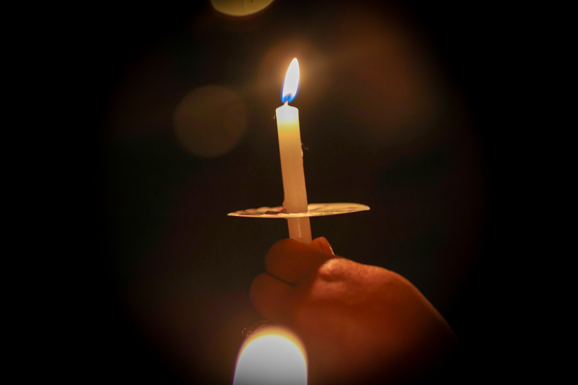 a black woman holding a lit candle in her hand